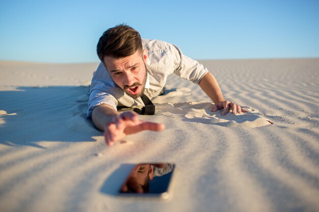 Слабый сигнал. бизнесмен ищет сигнал мобильного телефона в пустыне