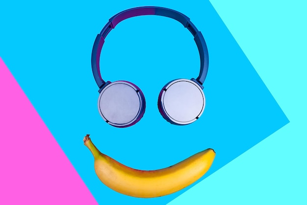 Pop art flat concept of banana and headphones on vivid colored background forming a smile face. Flat style and colors