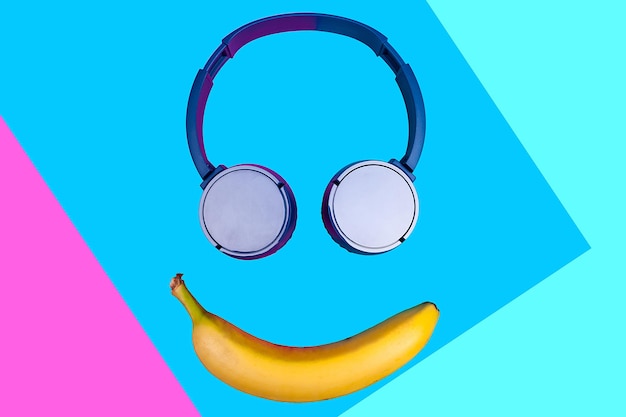 笑顔を形成する鮮やかな色の背景にバナナとヘッドフォンのポップアートフラットコンセプト。フラットなスタイルと色