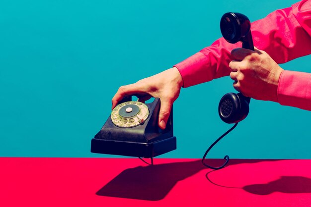 Pop art photography Colorful image of retro phone on bright pink tablecloth isolated over blue background