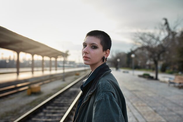 Pop punk aesthetic portrait of woman posing in train station