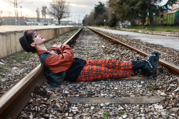 Поп-панк эстетический портрет женщины, позирующей на железнодорожных путях