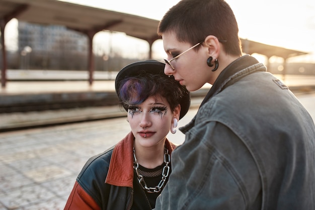 Ritratto estetico pop punk di donne in posa nella stazione ferroviaria