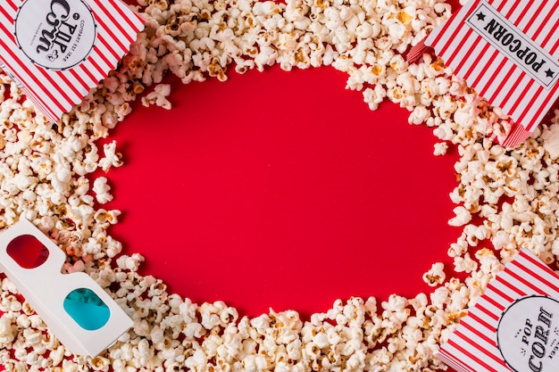 Free photo popcorn and 3d glasses with copy space for writing the text on red backdrop