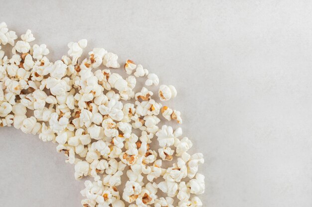 Popcorn arranged in an arc on marble table.