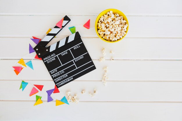 Popcorn bowl near clapperboard and pennant garland