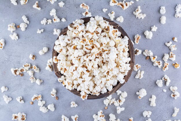 Popcorn in a bowl and scattered all over on marble surface