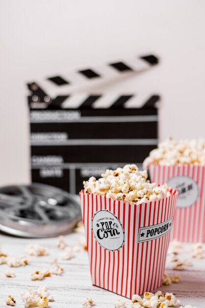 Popcorn boxes with film reel and clapperboard on wooden desk