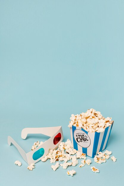 Popcorn filled in the box with 3d glasses against blue backdrop