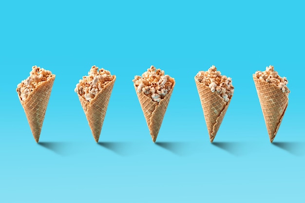 Попкорн в конусах мороженого на синем фоне. скопируйте пространство. натюрморт. шаблон