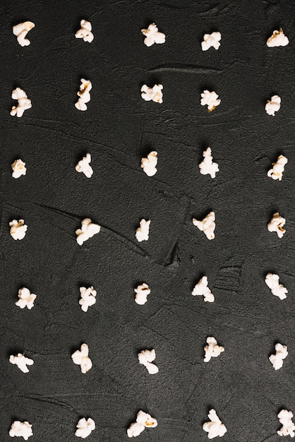 Popcorn lying in order on black background