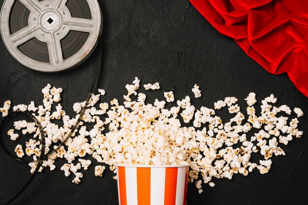 Popcorn near film reel and red cloth