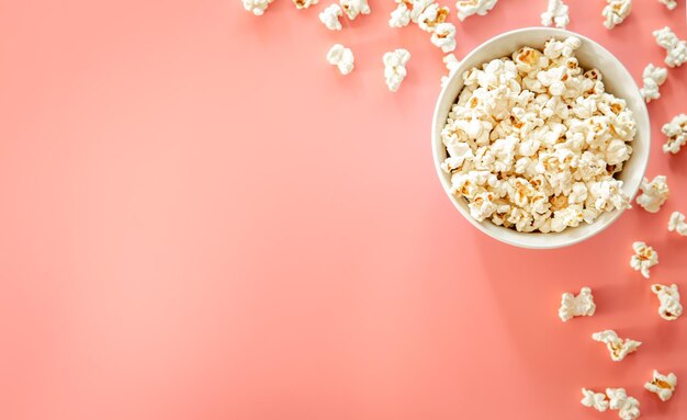 Popcorn plate on pink background flat lay