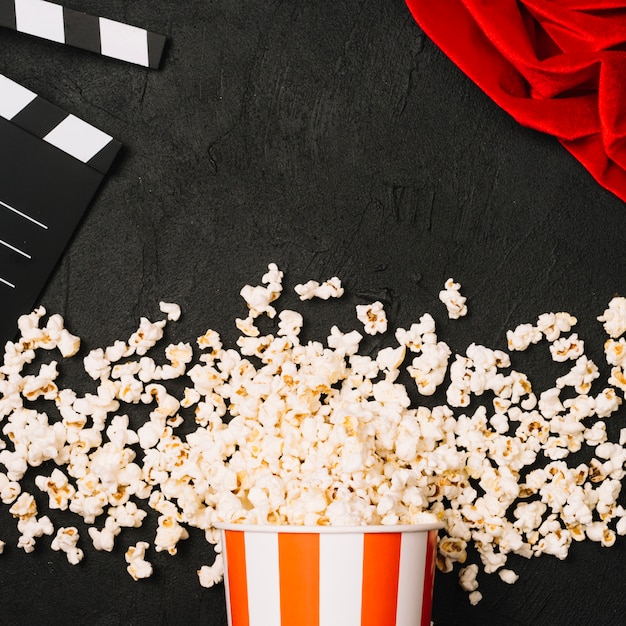 Popcorn spilled near clapperboard and red cloth