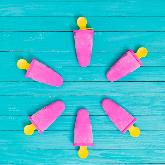 Popsicle bright pink on yellow chopsticks on turquoise table