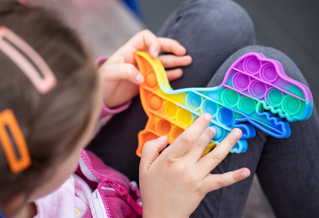 Foto gratuita il popolare giocattolo colorato antistress a forma di drago si agita spingendolo nelle mani di un bambino