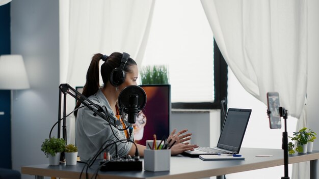 Popular internet streamer answering public question on live chat while broadcasting video. Young digital content creator talking to audience while recording daily vlog at home.