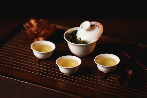 Porcelain gaiwan, three cups of Chinese tea and golden frog on tea desk.