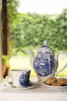 Free photo porcelain teapot and teacups with whale shaped cookie on table at outdoors