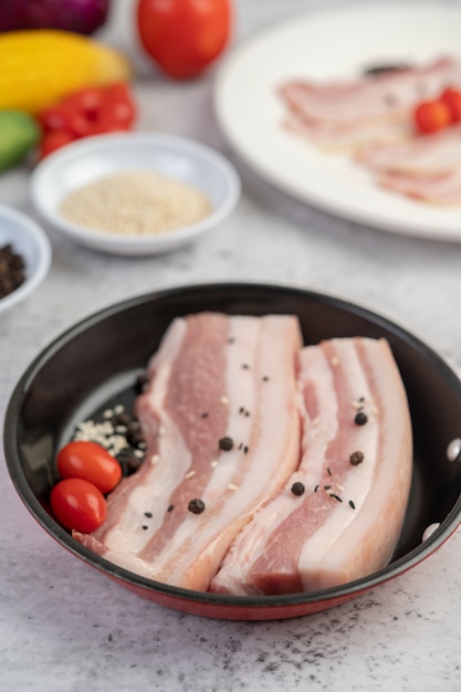 Free photo pork belly in a pan with pepper seeds tomatoes and spices