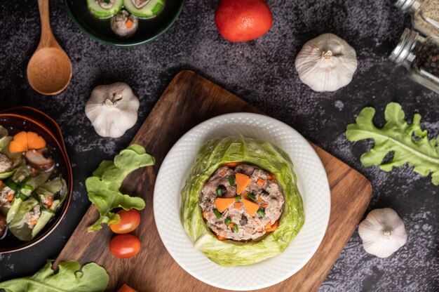 Pork cabbage soup with carrots, chopped green onions, cucumber in a wooden plate on a wooden plate