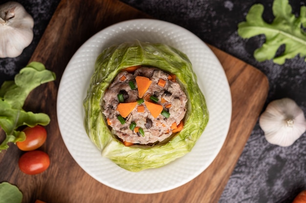 Pork cabbage soup with carrots, chopped green onions, cucumber in a wooden plate on a wooden plate