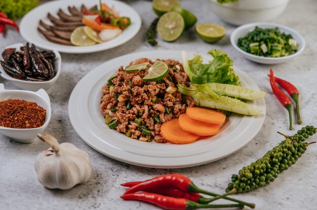 Pork Larb with carrot, cucumber, lime, spring onion, chili, freshly ground pepper, and lettuce.