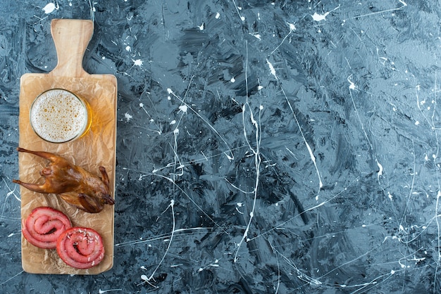 Free photo pork lard, grill and beer on cutting board on blue.