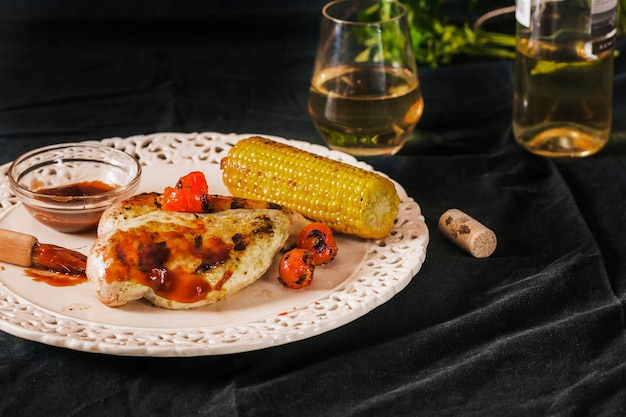 Pork served with cherry tomatoes and corncob on plate