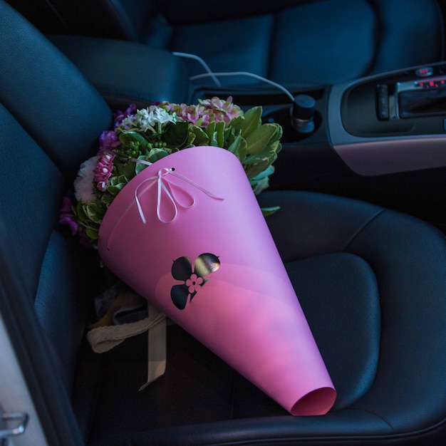 Un mazzo di carta portatile di fiori in piedi su un sedile in una macchina