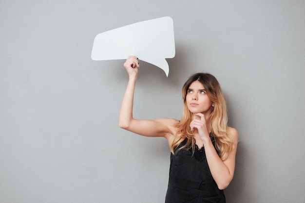 Free photo portait of a lovely pensive woman holding speech bubble