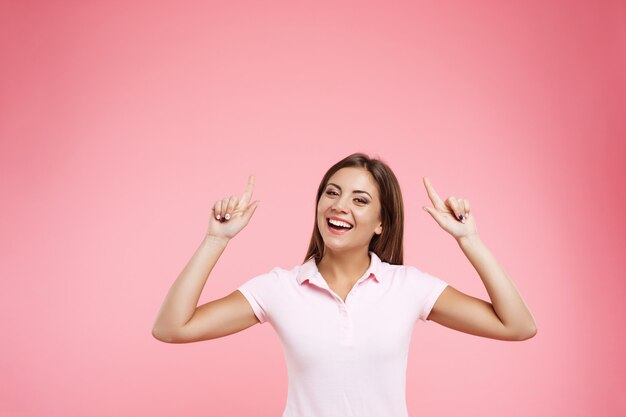 Portait of woman in pink polo posing with hands up