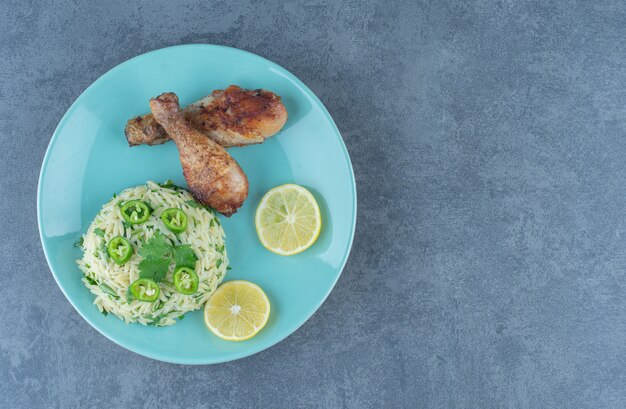 Portion of rice with chicken legs on blue plate. 