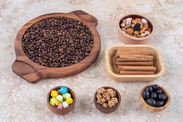 Portions of candies, assorted nuts, glazed peanuts, cinnamon sticks and coffee beans 