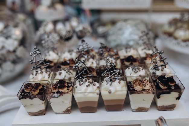 Portions of tiramisu and mousse desserts stand on the catering table