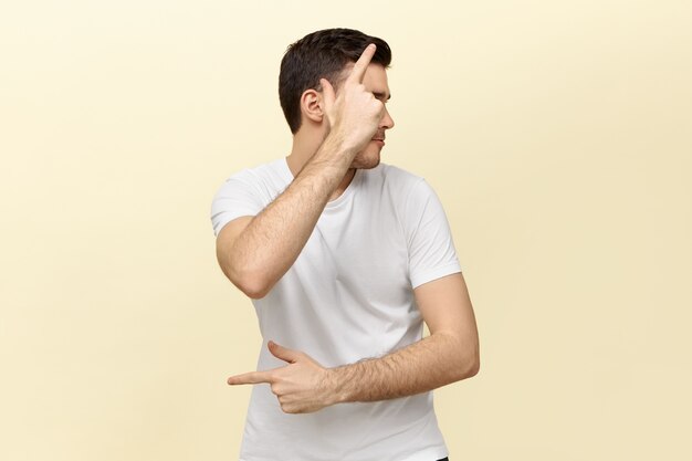 Portrait of active energetic young man having fun making gestures as if holding pistol