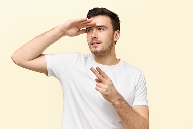 Portrait of active energetic young man having fun making gestures as if holding pistol