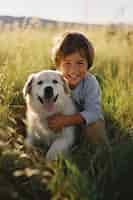 Foto gratuita ritratto di un bambino adorabile con il suo cane sul campo