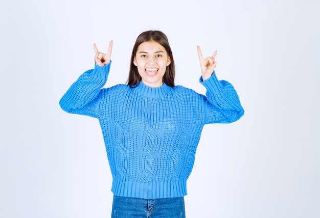 Портрет очаровательной девушки в голубом свитере, давая жесты на белом.