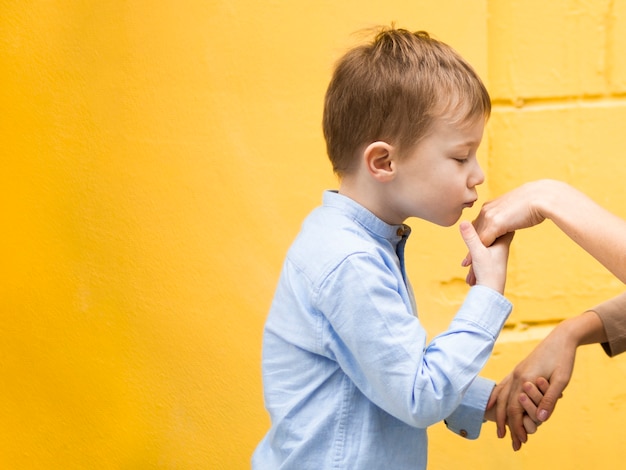 Portrait of adorable young boy kissing his mothers hand