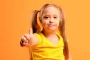 Free photo portrait of adorable young girl with thumbs up