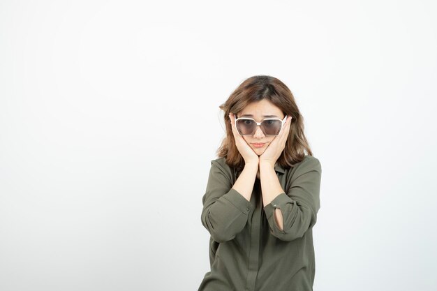 Portrait of adorable young woman in eyeglasses standing over white. High quality photo