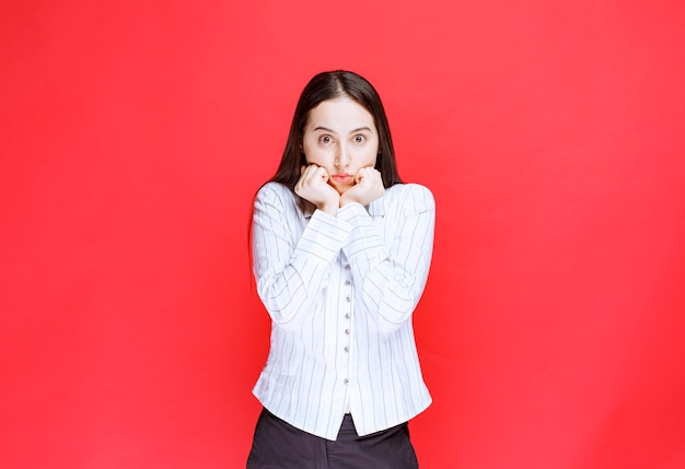 Portrait of adorable young woman looking at camera on red background. 