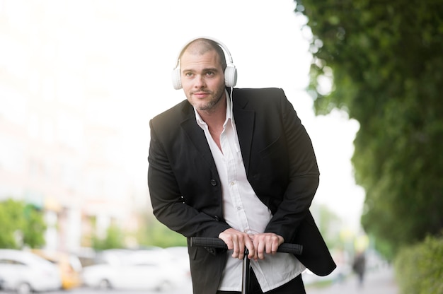 Portrait of adult male riding scooter with headphones