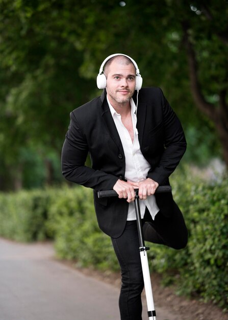 Free photo portrait of adult male riding scooter with headphones