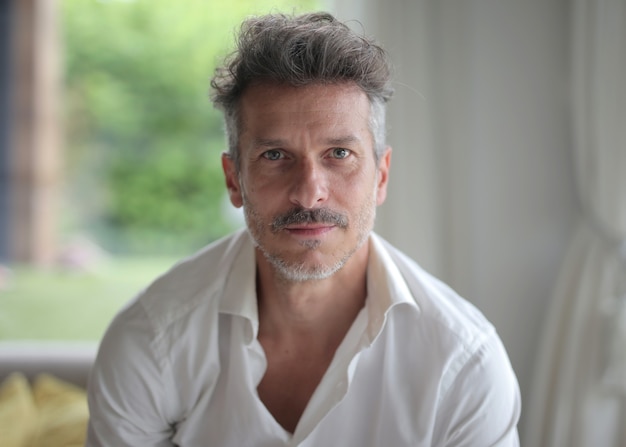 Portrait of an adult male with a quiff and blue eyes under the lights with a blurry surface