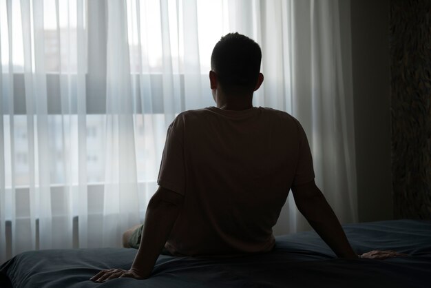 Portrait of adult man with curtains and shadow from window