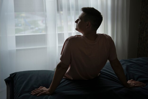 カーテンと窓からの影を持つ成人男性の肖像画