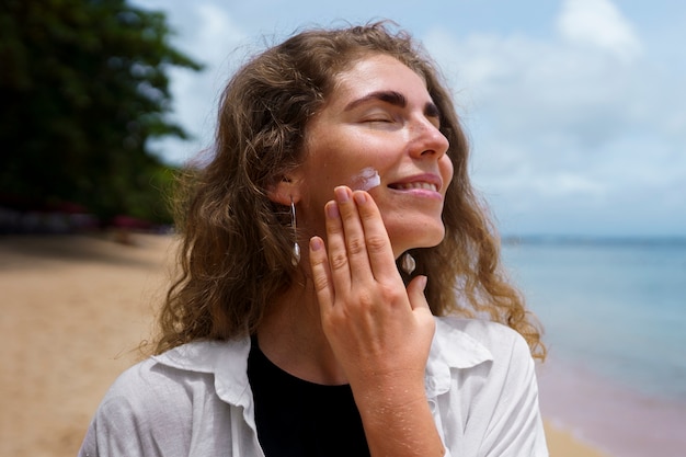 Portrait of adult woman applying lotion on sunburn skin