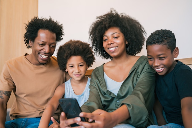 Foto gratuita ritratto della famiglia afroamericana che cattura un selfie insieme al telefono cellulare a casa. concetto di famiglia e stile di vita.